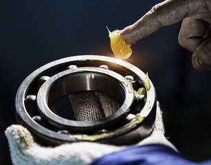 Mechanic is putting yellow grease in the into bearing, engineering and industrial concept
